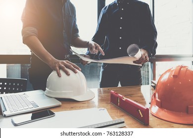 Two Construction Engineers Working At  Construction Site With Blueprint On Table