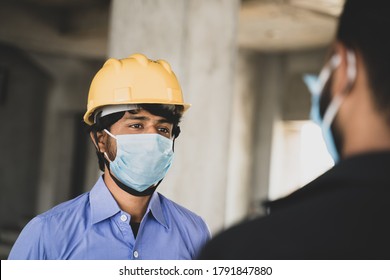 Two Construction Workers Or Engineers At Site Talking By Wearing Medical Face Mask While Maintaining Social Distance - Concept Of Business, Industry Reopen Or Covid-19 Safety Measures At Workplace