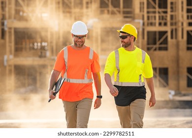 Two construction workers with hardhat helmet on construction site. Construction engineer workers in builder uniform. Two builders ready to build new house. Workers in hardhat at construction site.
