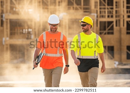 Two construction workers with hardhat helmet on construction site. Construction engineer workers in builder uniform. Two builders ready to build new house. Workers in hardhat at construction site.
