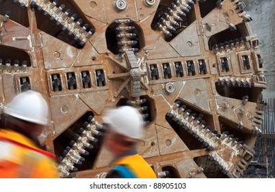 Two construction workers with helmets looking at tunnel boring machine