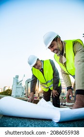 Two Construction Workers Are Smiling And Looking At The Plans, Low Angel