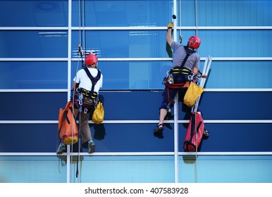 Two Construction Workers Working At Height On Modern Commercial Skyscraper.