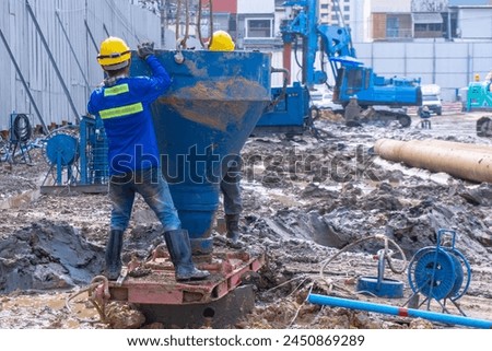 Two Constuction piling worker holding Concrete bucket for pouring concrete to Bored pile in site constuction 