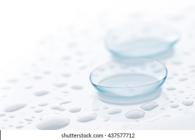 Two contact lenses close-up on white background with water drops. Shallow DOF.