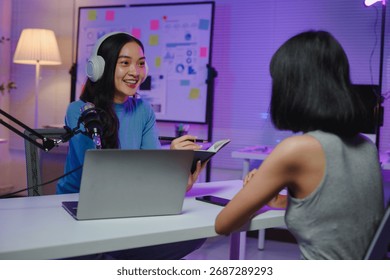 Two content creators collaborating, recording podcast audio with professional microphone near laptop in home workspace