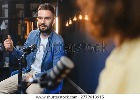Two content creators engaging in a lively podcast recording session, utilizing a professional microphone in a stylish home studio setting