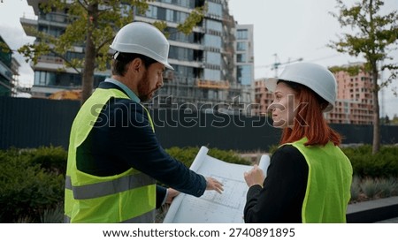 Two contractors civil engineers checking blueprint discuss buildings project teamwork woman man pointing city managers planning collaboration construction workers urban development plan information