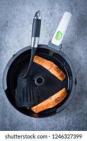 Two Cooked Filets Of Salmon In An Air Fryer With A Spatula On A Dark, Grunge Background. Healthy Salmon Meal. Air Fried Salmon Filet.