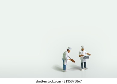 Two Cooks In Work Clothes And Cookware On White Background