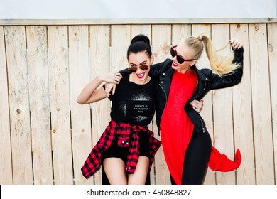 Two Cool Trendy Bold Girl In Casual Black And Red Clothes, Laughing, Going Crazy On The Wooden Background, Blonde And Brunette. Stylish Hairstyle And Makeup. Vogue Style. Fashion Beauty Swag Girl.