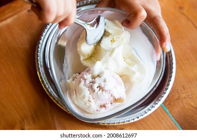 Two Coop Of Ice Cream In Transparent Glass Bowl. Child Eats Frozen Yogurt In Summer Caffe. Fingers And Spoon. Homemade Ice Cream For Children. 