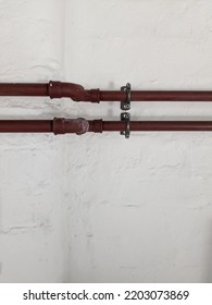 Two Copper Pipes Running Across A White Painted Stone Wall