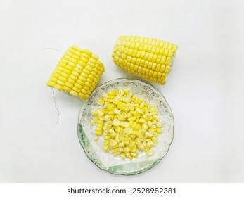 Two corn halves with additional corn slices arranged on a small plate, emphasizing their bright yellow hue and fresh texture.
