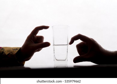 Two Couple Are Showing Half Full And Half Empty Side Of Water Glass With Their Fingers