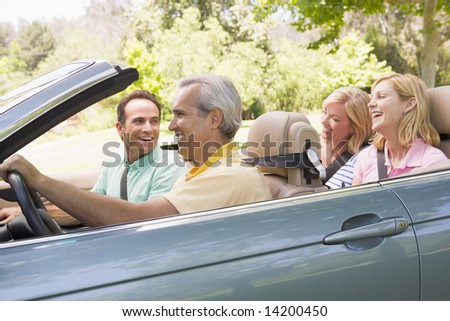 Two couples in convertible car smiling