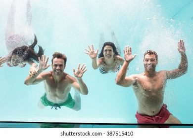 Two couples enjoying and swimming underwater in swimming pool - Powered by Shutterstock