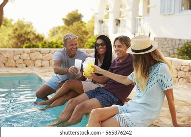 Two couples make a toast with legs dipping in swimming pool - Powered by Shutterstock