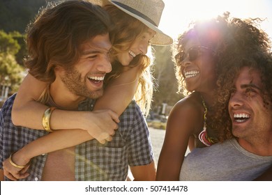 Two couples piggybacking at the beach, looking at each other - Powered by Shutterstock