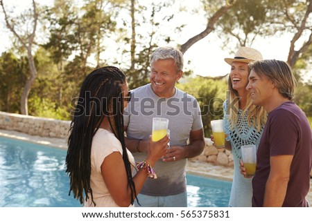 Two couples standing in a garden by a swimming pool talking