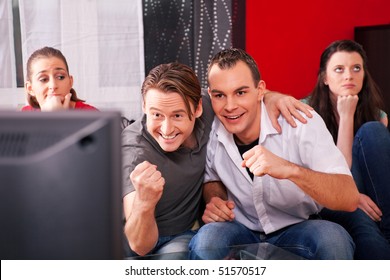 Two Couples Watching Sports In The Telly, The Guys Are Really Excited And Cheer Their Team While The Girls Are Quite Bored