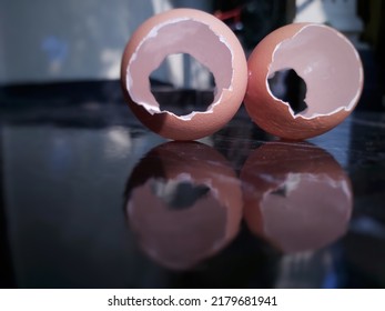 Two Cracked Chicken Egg Shells On The Dark Black Ceramic Floor, Blurred Style, Abstract Background