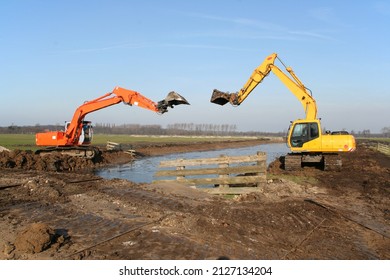 Two cranes with backhoes involved in canal bank improvement in a typical Dutch polder landscape 