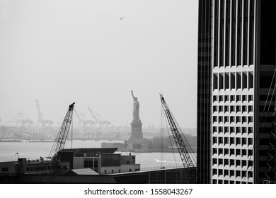two cranes next to a skyscraper with the statue of liberty in the background, New York, NY, United States