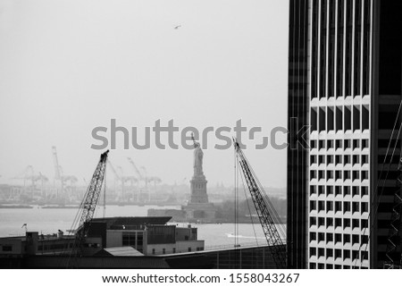 two cranes next to a skyscraper with the statue of liberty in the background, New York, NY, United States