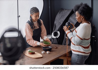 Two creative African American female photographers working together in studio and setting up food photography set in professional studio copy space - Powered by Shutterstock