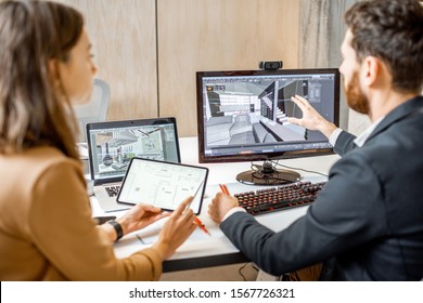 Two Creative Office Employees Making Interior Design On The Computer And Digital Tablet At The Modern Office Of Architectural Firm. Concept Of 3d Modeling And Digital Interior Designing