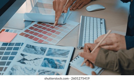 Two creative professionals engage in a collaborative process, selecting color palettes and reviewing design materials in a modern workspace filled with digital tools. SACTR