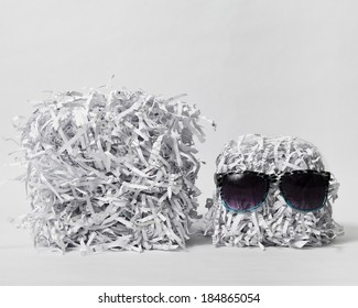 Two cubes made of compacted shredded paper, one is wearing sunglasses, against a white background.
