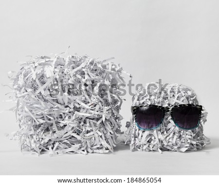 Two cubes made of compacted shredded paper, one is wearing sunglasses, against a white background.