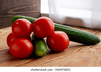 two cucumbers and five tomatoes on a wooden background. High quality photo