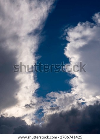Two cumulus clouds separated by a pronounced vertical gap with intervening cloudlets at the bottom on a spring evening in southwest Florida. Motifs of wind flow, separation, and cloud dynamics.