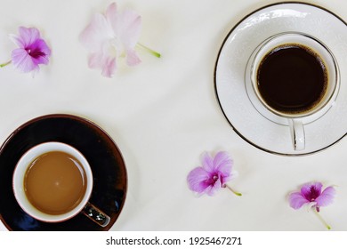 Two Cups Of Beverage Milk Coffee And Black Coffee Placed On The Table Cloth Decorate With Orchid Flower