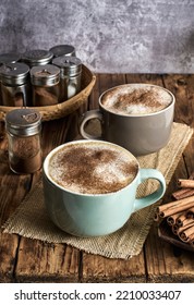 Two Cups Of Caffe Latte Topped With Cinnamon Powder Served In A Cozy Coffee Shop.