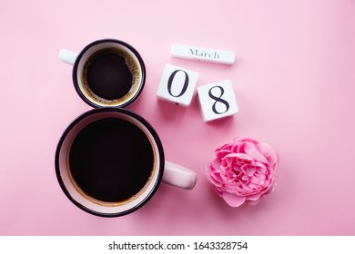 Two cups of coffee, a delicate flower and numbers. Greeting card for Women's Day March 8th. Trendy pink background. March 8 and the concept of "Women's Day".