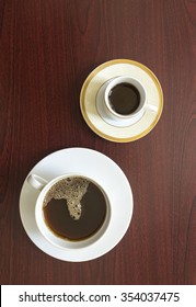 Two cups of coffee, includes arabic coffee cup , placed on wooden background. Bird eye view
