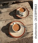 Two cups of coffee placed on a wooden table with a classic wooden surface