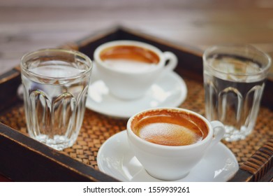 Two cups of coffee placed on a wooden tray selective focus.