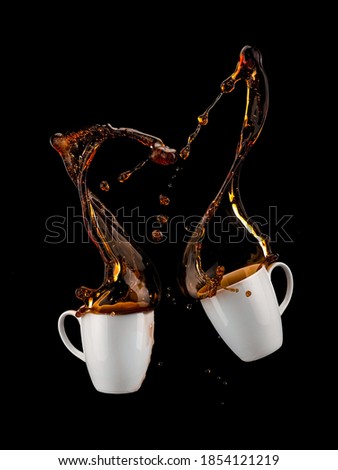 Two cups of coffee splash on black background