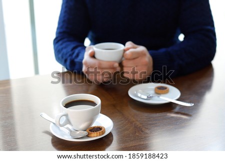 Two cups of coffee withma n hands on the wooden table in cafe background Foto stock © 