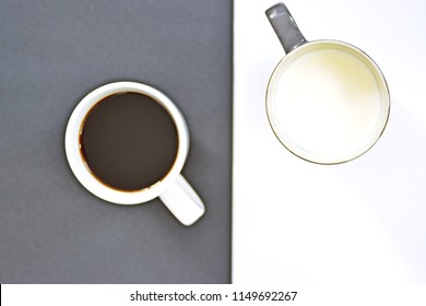 Two cups in front of a half black and half white background, one cup contains coffee, the other milk and both creat a contrast, concept for yin and yang with coffee cups