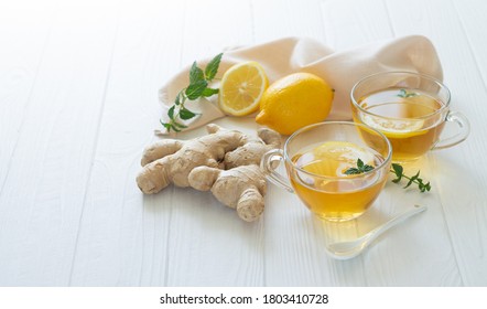 Two cups of healthy ginger tea with mint leaves and lemon on white table. Space for your text - Powered by Shutterstock