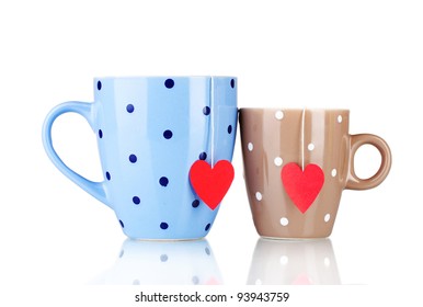 Two cups and tea bags with red heart-shaped label isolated on white