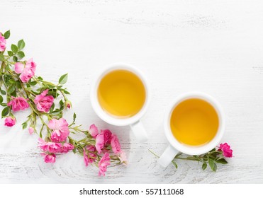 Two Cups  Of Tea And Branch Of Small Pink Roses On Rustic Table.