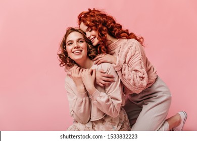 Two Curly Girls Embracing On Pink Background. Blissful Friends Having Fun Together.