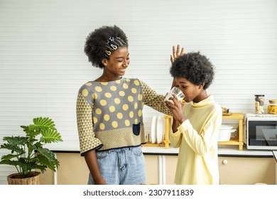 Two cute adorable siblings african american children having breakfast with milk at kitchen, Portrait of happy brother drinking milk with his sister and thumbs up, Food and drink concept - Powered by Shutterstock